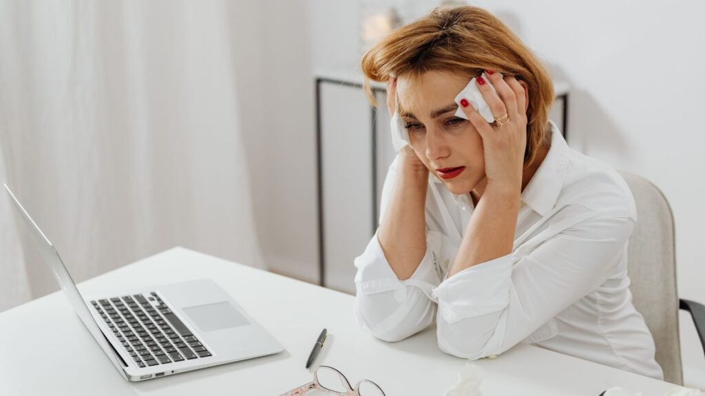 Mujer angustiada frente a su computadora con las manos en la cabeza durante un momento de ansiedad